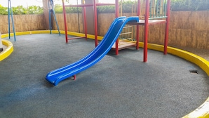 A playground with a blue slide and red and yellow safety borders. - Comfy and Modern Studio at Serpong Greenview Apartment (South Tangerang)