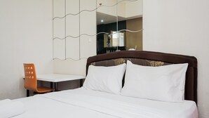 A hotel room with a neatly made bed, a small table, and a chair. - Comfy and Modern Studio at Serpong Greenview Apartment (South Tangerang)