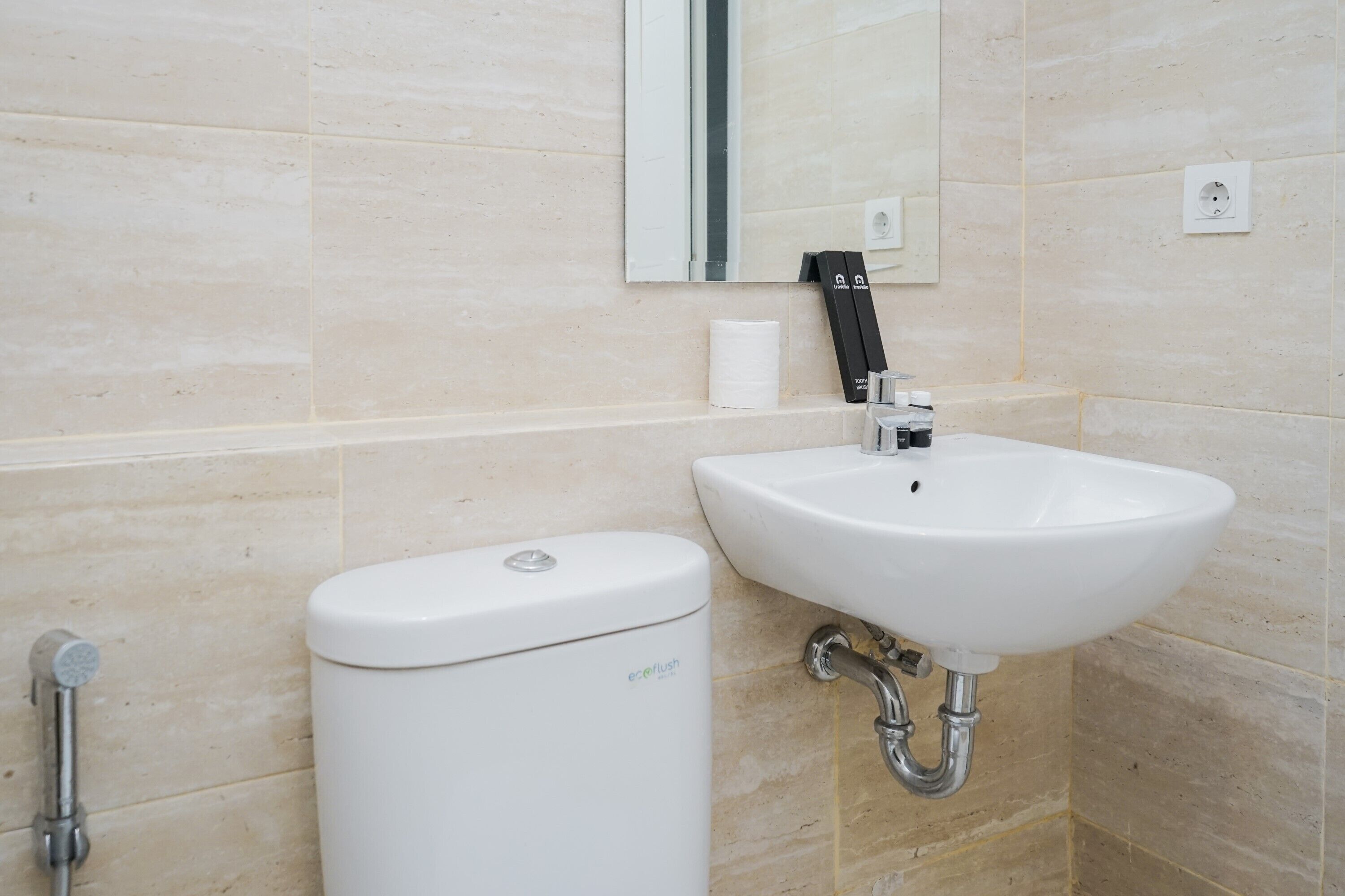 Une salle de bain avec des toilettes blanches, un lavabo et un miroir.