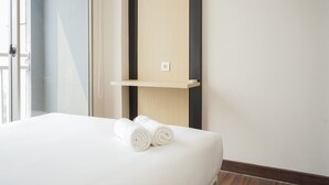 Ein Hotelzimmer mit einem Bett, einer Holzablage und zwei gerollten Handtüchern.