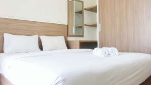 A neatly made bed with white linens and two pillows, a wooden headboard, and a mirror on the wall. - Strategic and Comfy 2BR Apartment Springwood Residence (Tangerang)