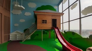 A play area with a wooden playhouse, a red slide, and a green hill. - Luxury Studio at Springwood Residence Tangerang Apartment (Tangerang)