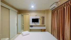Ein Hotelzimmer mit Bett, Wand-Fernseher, Schreibtisch mit Computer und Schiebetürenschrank.