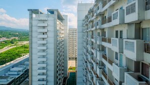 A high-rise building with multiple balconies, a central courtyard, and a view of a green landscape. - New Furnished Studio at Sentul Tower Apartment (Citaringgul)