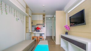 A modern kitchen with white cabinets, a wooden countertop, and a red kettle. - New Furnished Studio at Sentul Tower Apartment (Citaringgul)