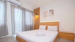 Een netjes opgemaakt bed met een houten hoofdbord, een nachtkastje en een wandlamp.