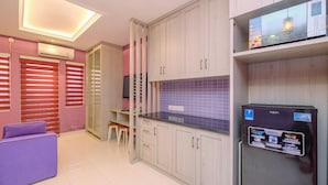 A modern kitchen with light-colored cabinets, a purple countertop, and a refrigerator with a water dispenser. - Homey and Modern Studio at Sentul Tower Apartment (Citaringgul)