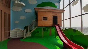 A play area with a wooden playhouse, a red slide, and a green hill. - Fully Furnished with Cozy Design Studio Springwood Residence Tangerang Apartment (Tangerang)
