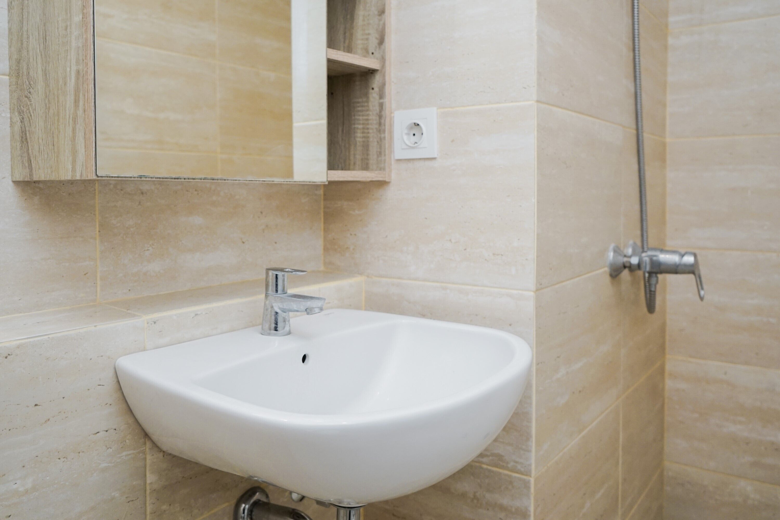 Un baño con lavamanos blanco, espejo y ducha.