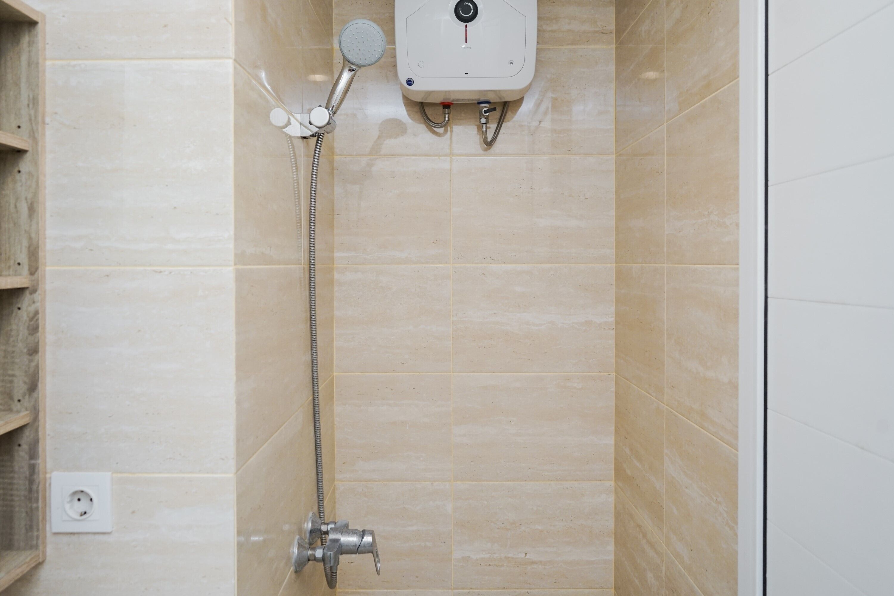 Een douche met een handdouche en een bedieningspaneel aan de muur.