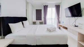 A hotel room with a large bed, a desk, a chair, a TV, and a window with curtains. - Nice Studio at Springwood Residence Tangerang Apartment (Tangerang)