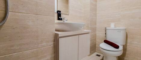 Un baño moderno con un lavamanos, espejo y retrete blancos.