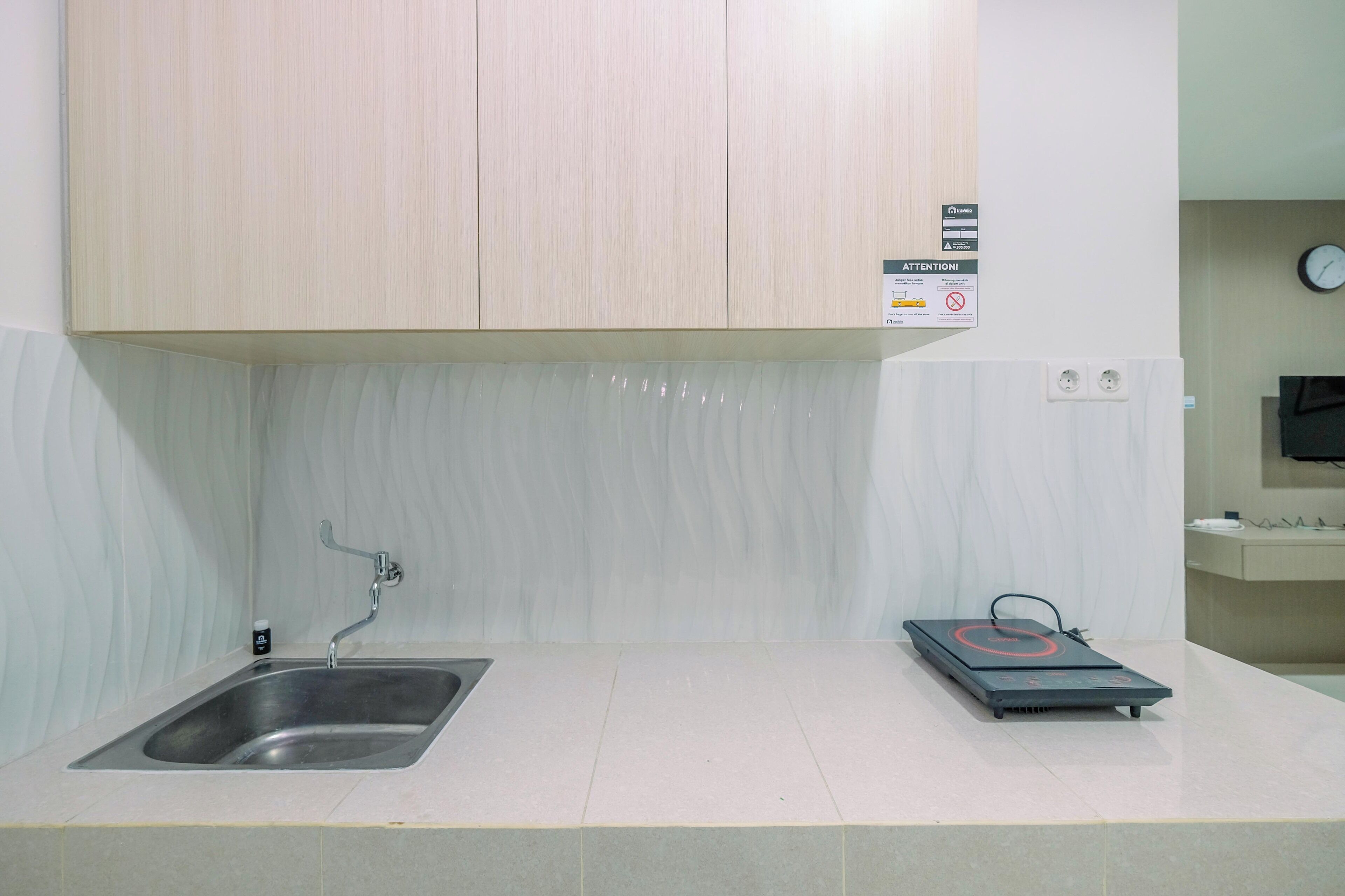 A kitchen with a stainless steel sink, a built-in oven, and a wall-mounted clock.