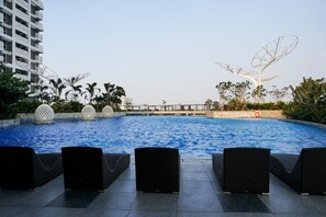 A swimming pool with lounge chairs and decorative elements. - Comfortable Studio at West Vista Apartment (Jakarta)