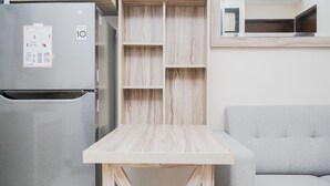 A kitchen with a stainless steel refrigerator, a wooden table, and a grey sofa. - Comfort and Minimalist 2BR Apartment Springwood Residence (Tangerang)