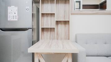 A kitchen with a stainless steel refrigerator, a wooden table, and a grey sofa.