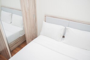 A neatly made bed with white linens and a wooden headboard. - Comfort and Minimalist 2BR Apartment Springwood Residence (Tangerang)