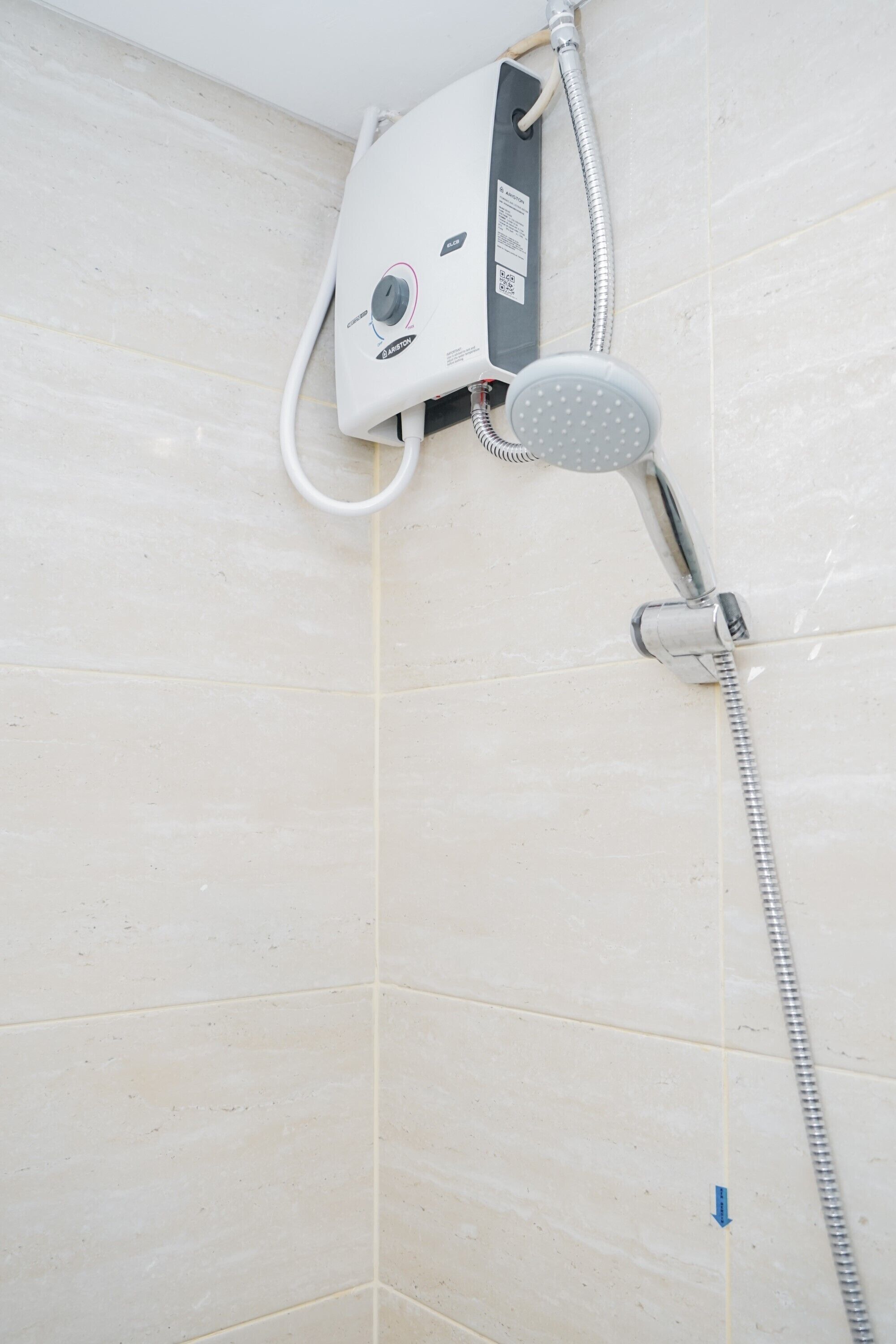 A shower with a handheld showerhead and a wall-mounted control panel.