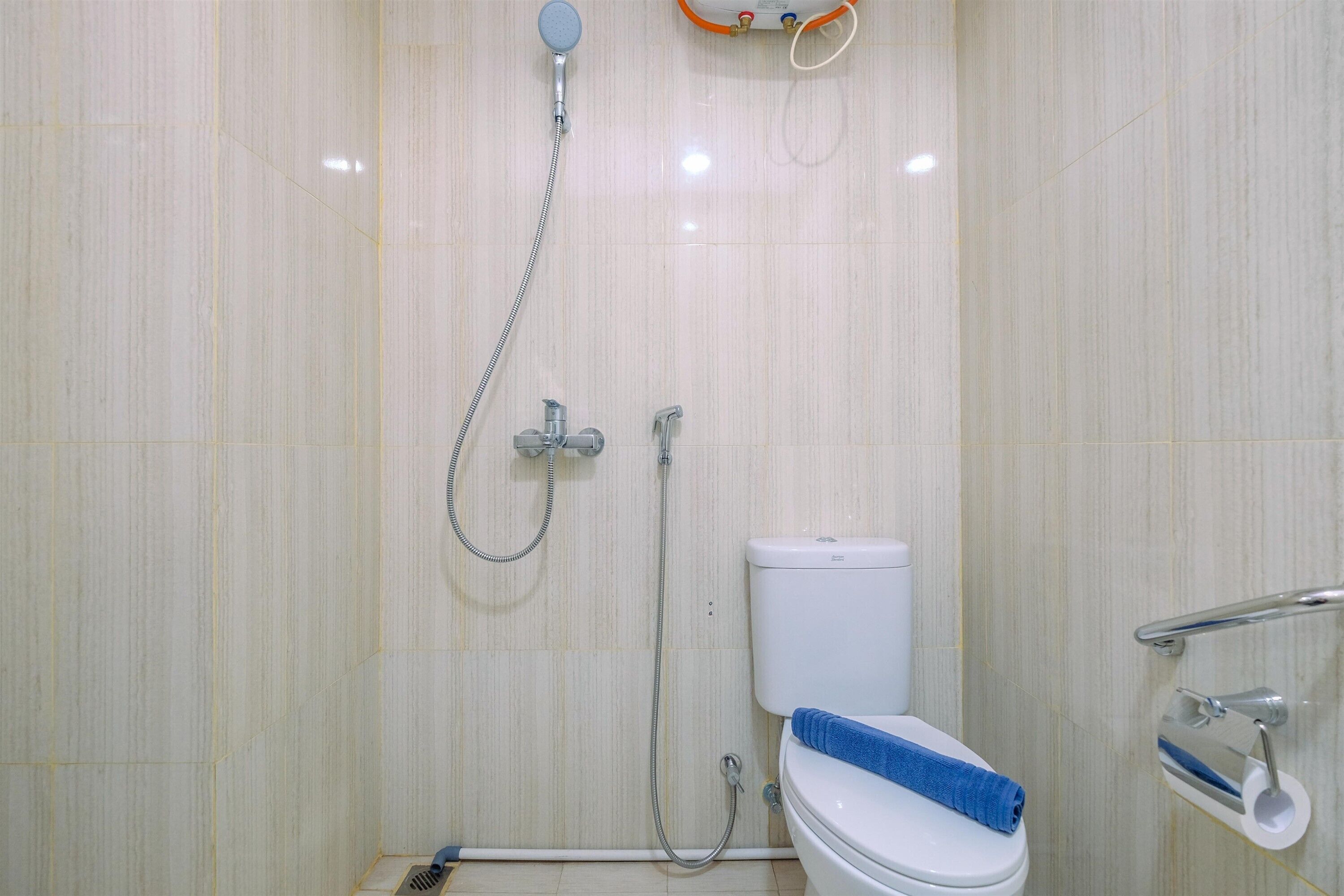 A bathroom with a toilet, a shower, and a towel rack.