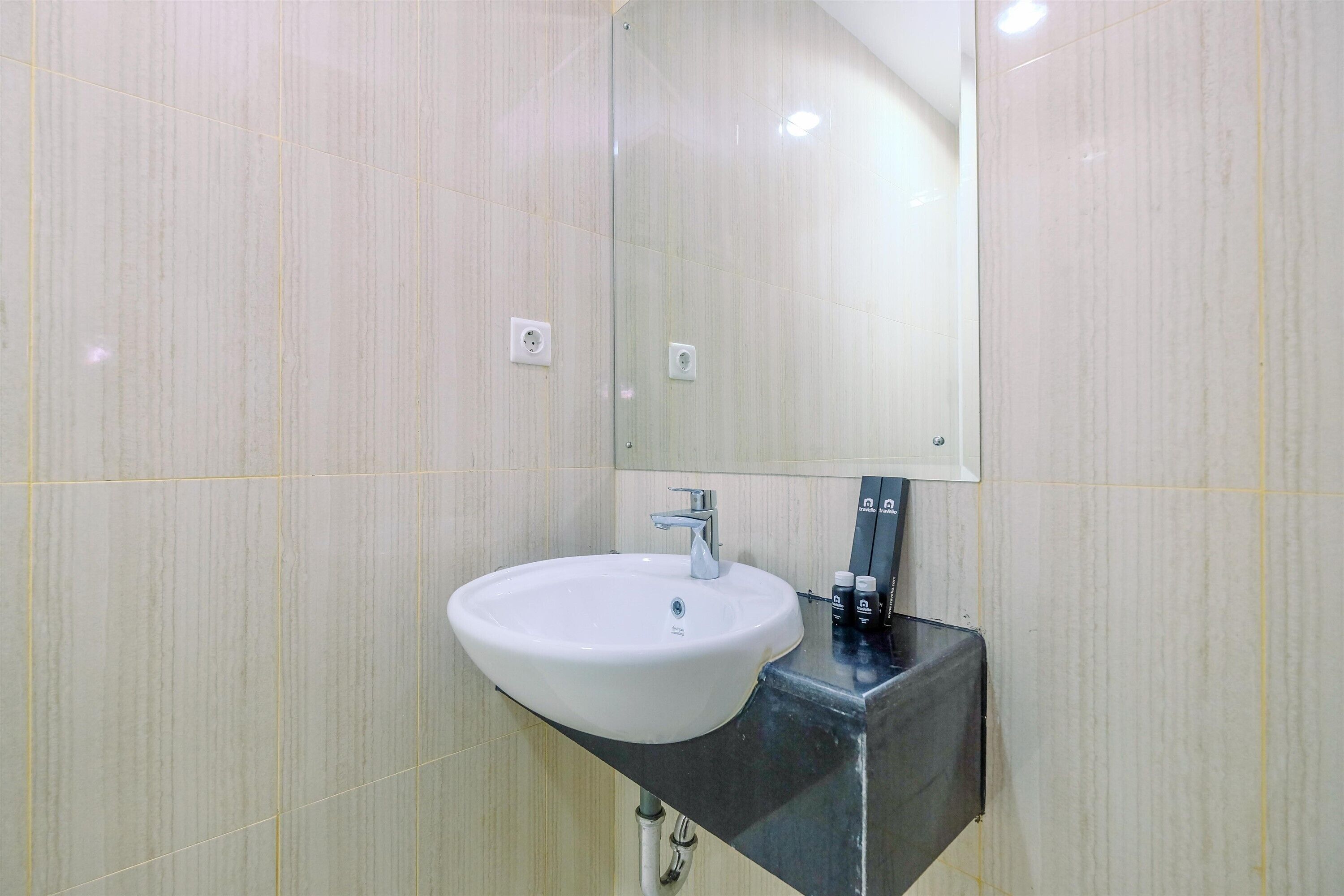 Un baño con lavamanos blanco, un espejo y encimera negra.