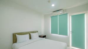 A bedroom with a bed, a nightstand, a window, and a door. - Homey 2BR at Sentul Tower Apartment (Citaringgul)