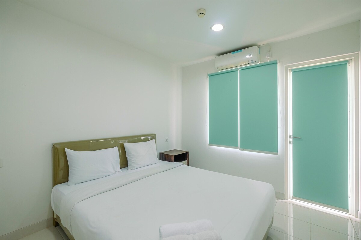 Un dormitorio con cama, mesita de noche, ventana y puerta.