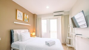 A hotel room with a bed, a TV, a shelf, and a window with curtains. - Cool and Warm Studio at Sentul Tower Apartment (Citaringgul)