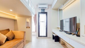 Una sala de estar moderna con un sofá, un televisor de pantalla plana y una ventana con cortinas.