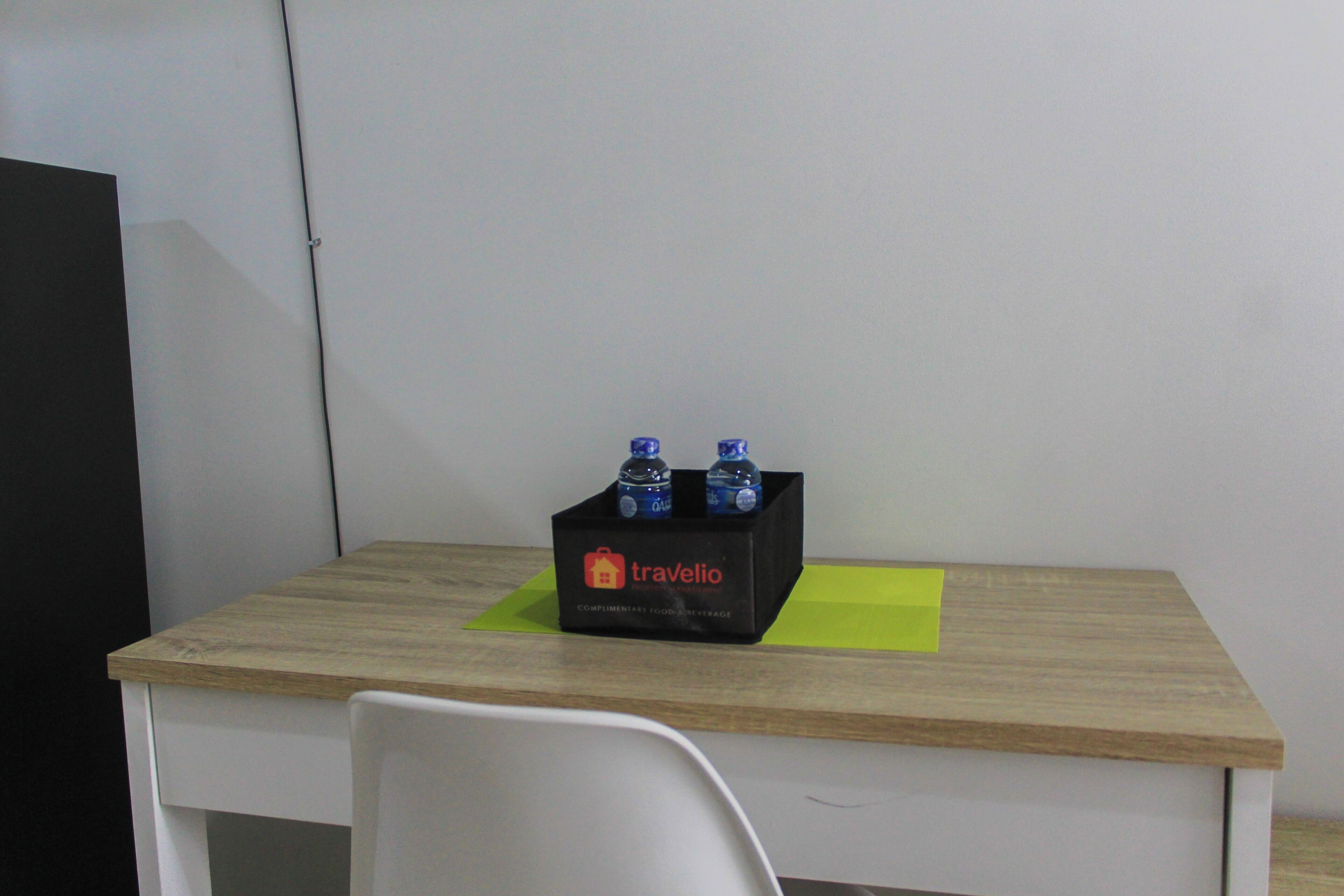 Escritorio de madera con una caja negra que contiene dos botellas de agua y una nota amarilla.
