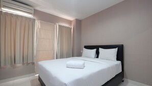A hotel room with a large bed, white bedding, a black headboard, and an air conditioning unit. - Relax 1BR Apartment at Sentul Tower (Citaringgul)