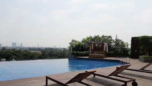 Area piscina sul tetto con poltronne da sole e una cabana.