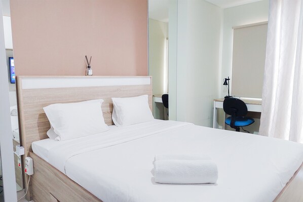 Cozy retreat with a neatly made bed, bedside table, and comfortable chair.