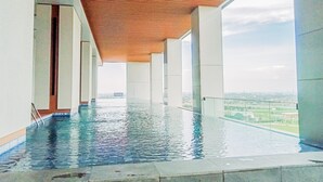A modern indoor swimming pool with a wooden ceiling and large windows offering a view of the city. - Cozy and Elegant Studio The Smith Alam Sutera Apartment (Tangerang)