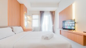 Ein Hotelzimmer mit Bett, Fernseher, einer Wand aus Holzpaneelen und einem Fenster mit Vorhängen.