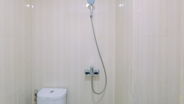 A bathroom with a shower, toilet, and a wall-mounted faucet. - Best Deal and Modern 1BR Sentul Tower Apartment (Citaringgul)