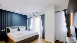 A modern hotel room with a wooden bed, a flat-screen TV, and a large window with curtains. - Best Deal and Modern 1BR Sentul Tower Apartment (Citaringgul)