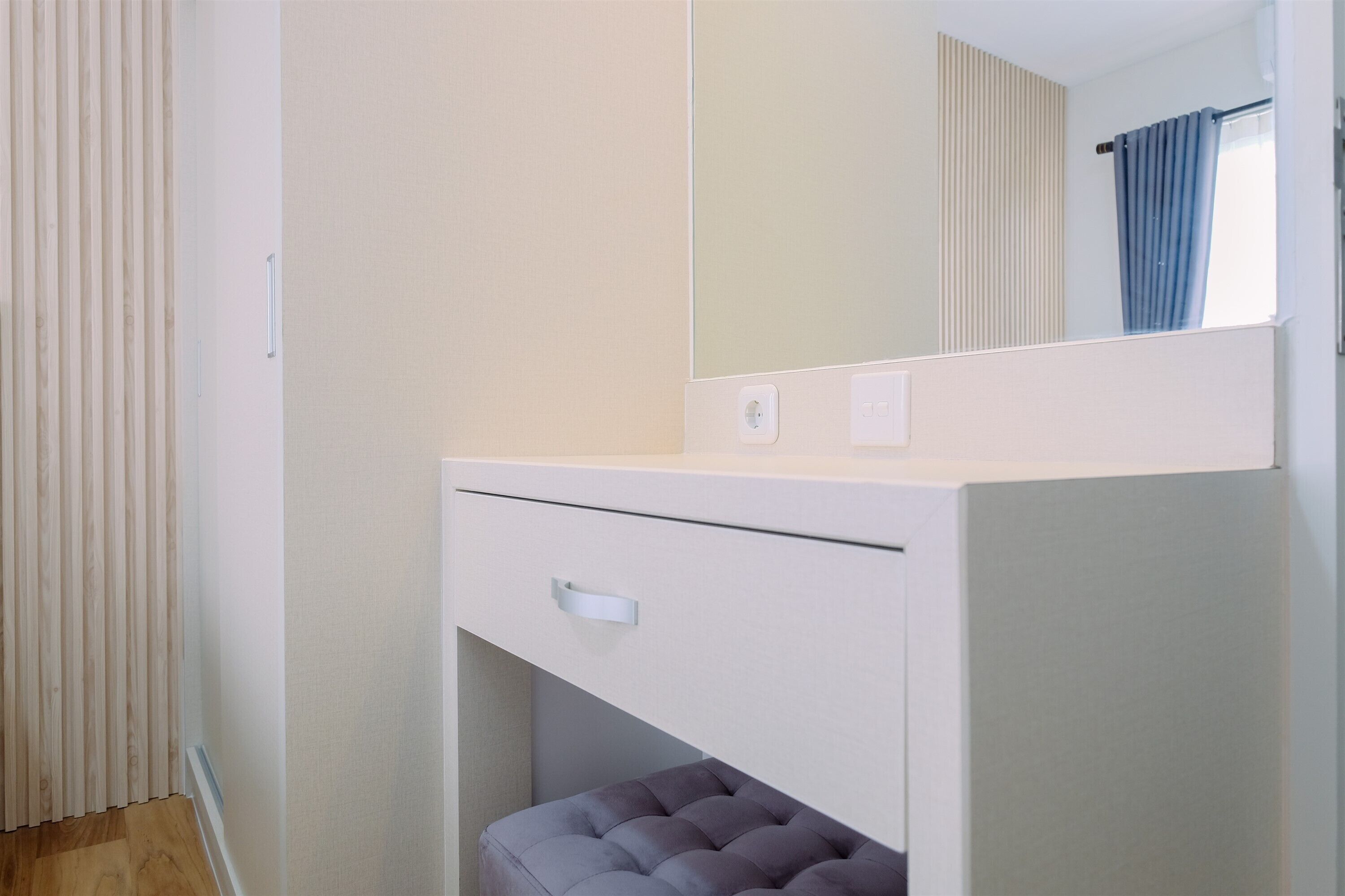 Ein Schlafzimmer mit Einbauschrank, Spiegel und einem Fenster mit Vorhängen.