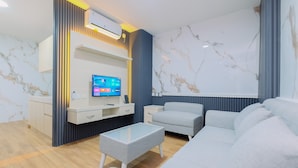 A modern living room with a sofa, a glass coffee table, and a TV mounted on a wall. - Restful and Modern 2BR at Sentul Tower Apartment (Citaringgul)