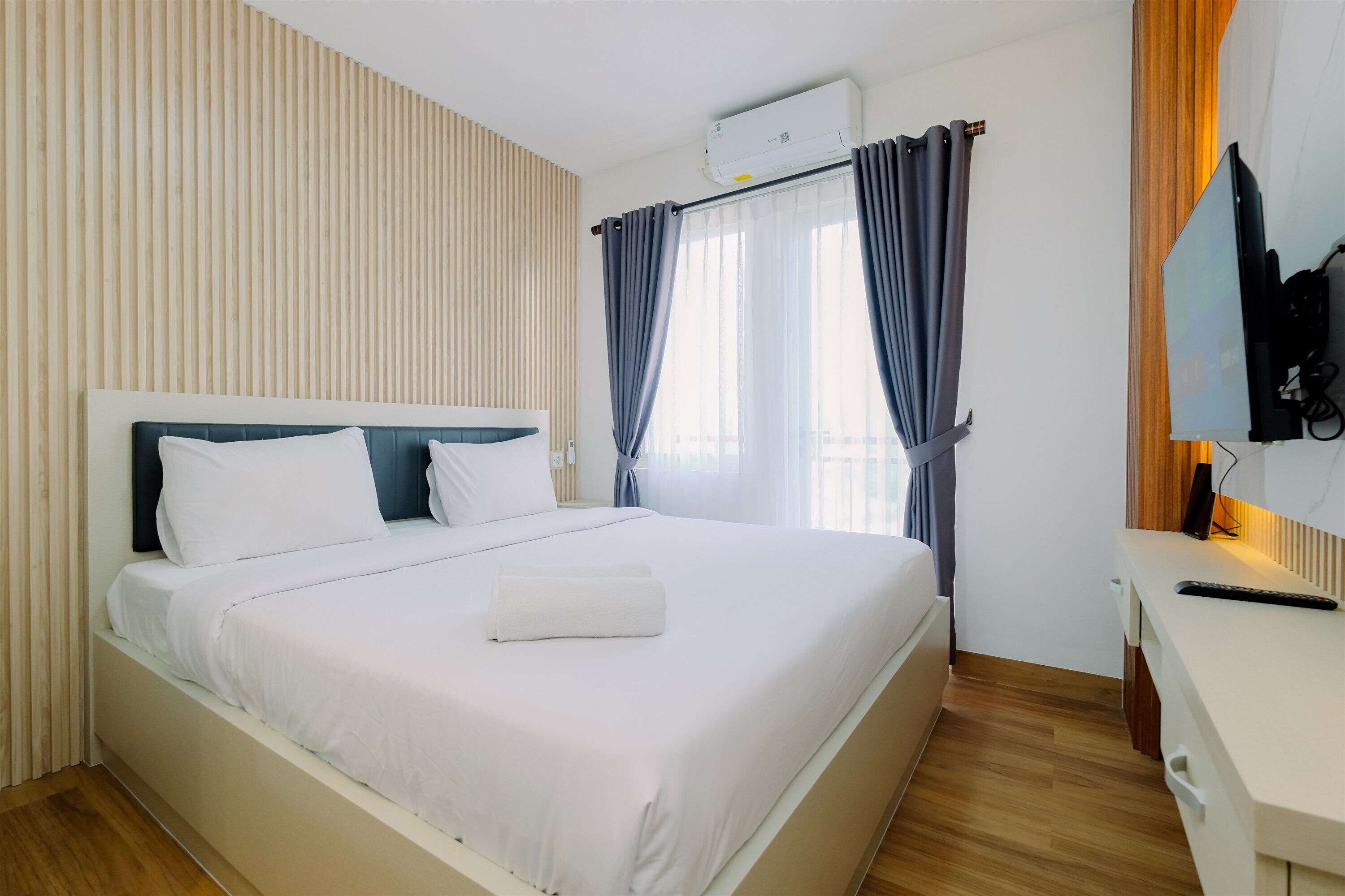 Une chambre d’hôtel avec un grand lit, un bureau doté d’un téléviseur à écran plat et un appareil de climatisation.