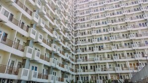 A high-rise residential building with multiple balconies, air conditioning units, and a uniform architectural design. - Restful and Modern 2BR at Sentul Tower Apartment (Citaringgul)