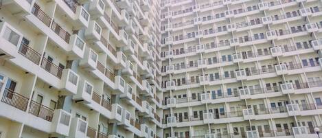 Un edificio residencial de gran altura con múltiples balcones, unidades de aire acondicionado y un diseño arquitectónico uniforme.