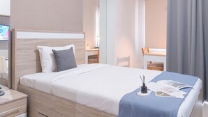 A hotel room with a bed, bedside table, and a desk with a chair. - Good Place and Homey Studio Springwood Residence Tangerang (Tangerang)