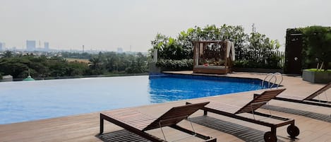 Una piscina en la azotea con dos tumbonas y vistas del horizonte urbano.