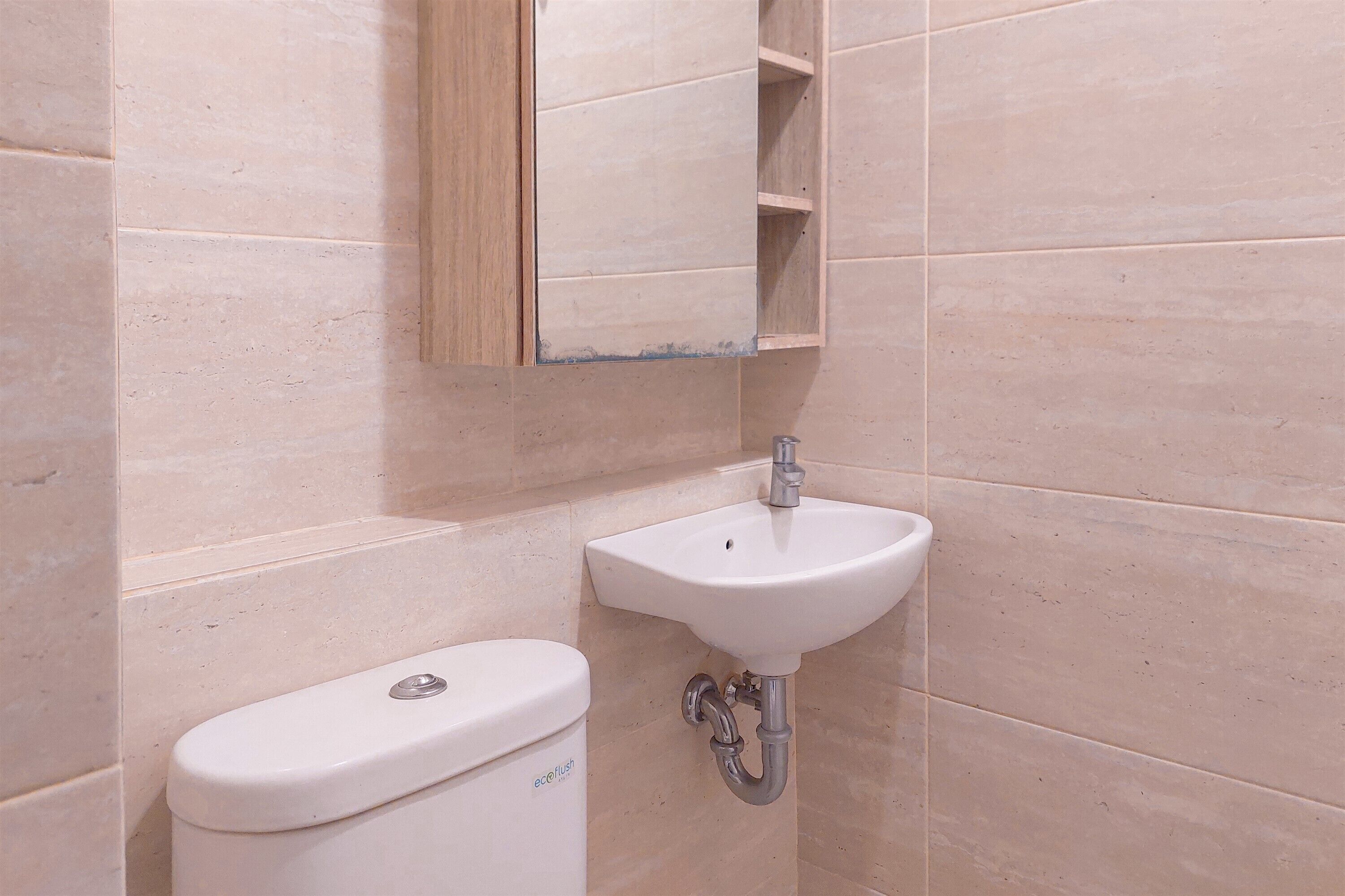 A bathroom with a white toilet, a sink, and a mirror.