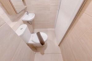 Un baño pequeño y moderno con inodoro, lavamanos y zona de ducha.