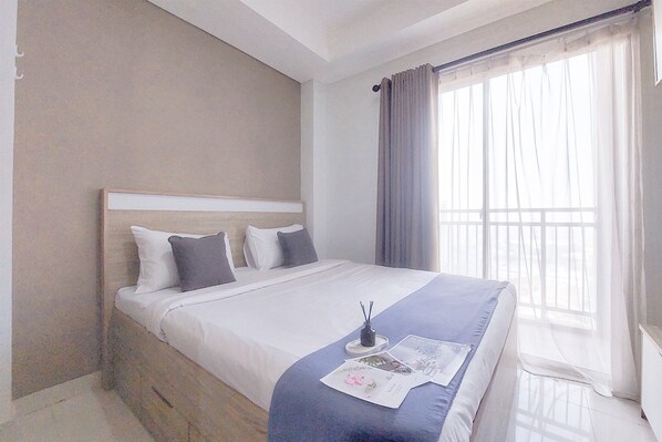 Habitación de hotel moderna con una cama grande, una mesita de noche y una ventana con cortinas.