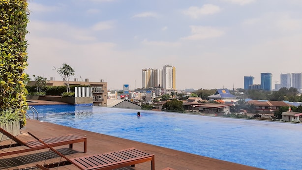 Une piscine sur le toit, dotée de chaises longues et offrant une vue sur la ville.
