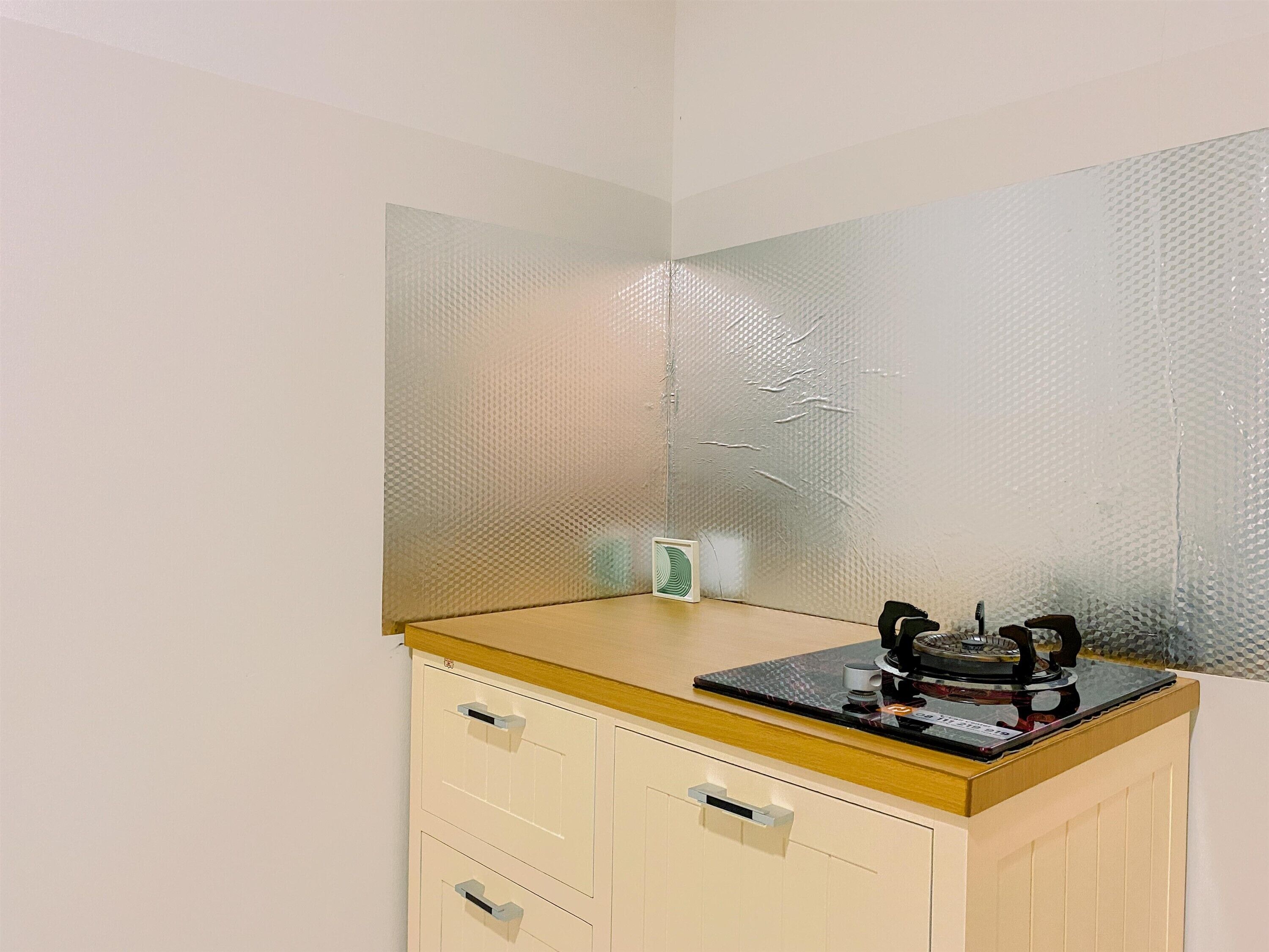 A small kitchenette with a gas stove, a microwave, and a small refrigerator.