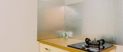 A small kitchenette with a gas stove, a microwave, and a small refrigerator.