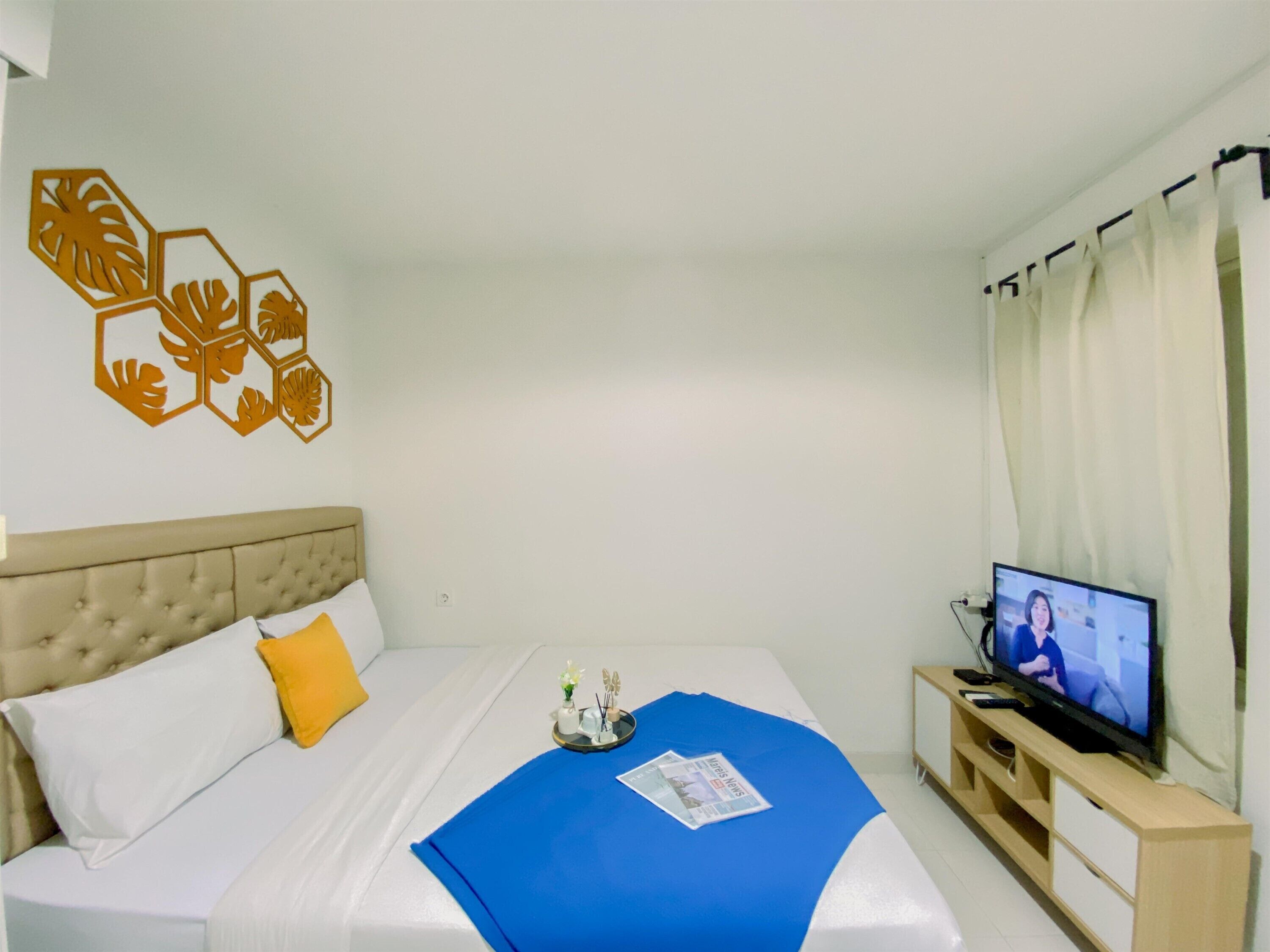 A hotel room with a bed, a television, and a wall decoration.